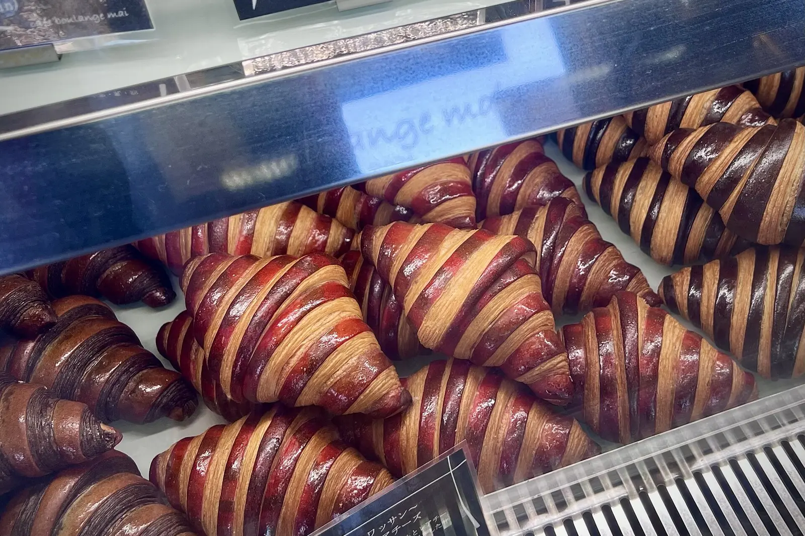 Striped chocolate and berry croissants in a bakery display case.