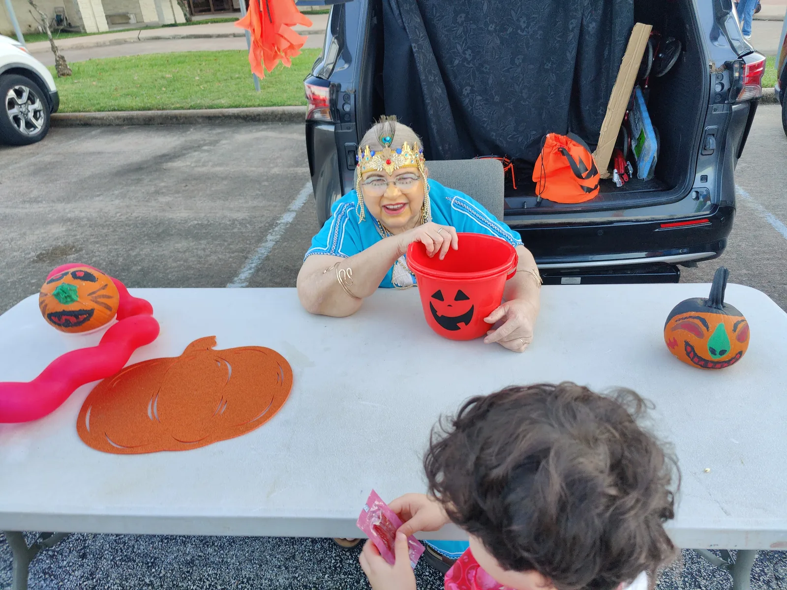A volunteer in costume hands out candy from a decorated minivan at the Westbury United Methodist Church trunk-or-treat.