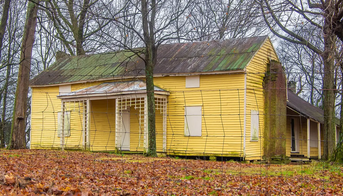 The yellow frame John Cloyd House, listed on the National Register of Historic Places, among bare trees and fallen leaves in Mount Juliet.