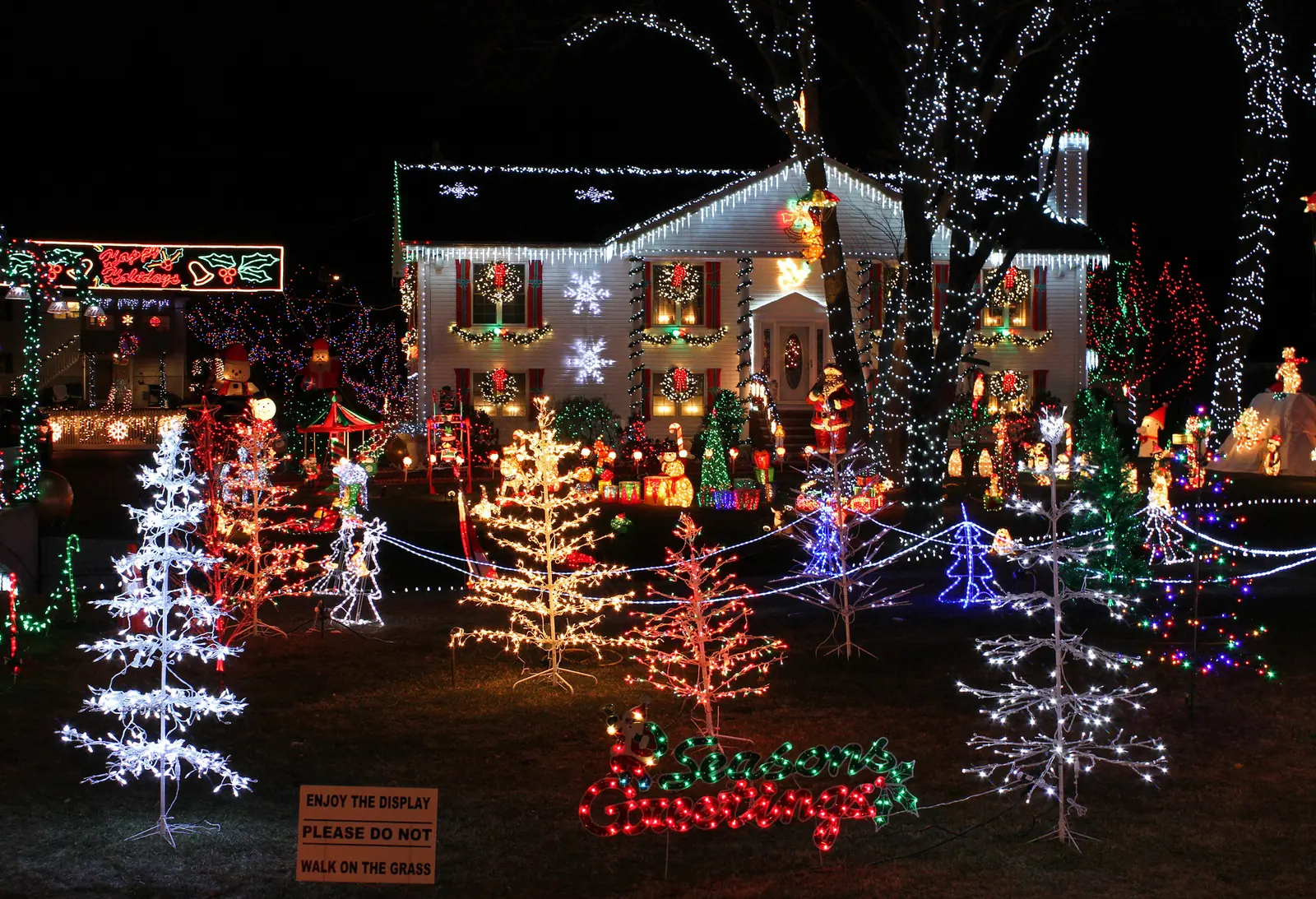 A house covered in Christmas lights and lit decorations at night.