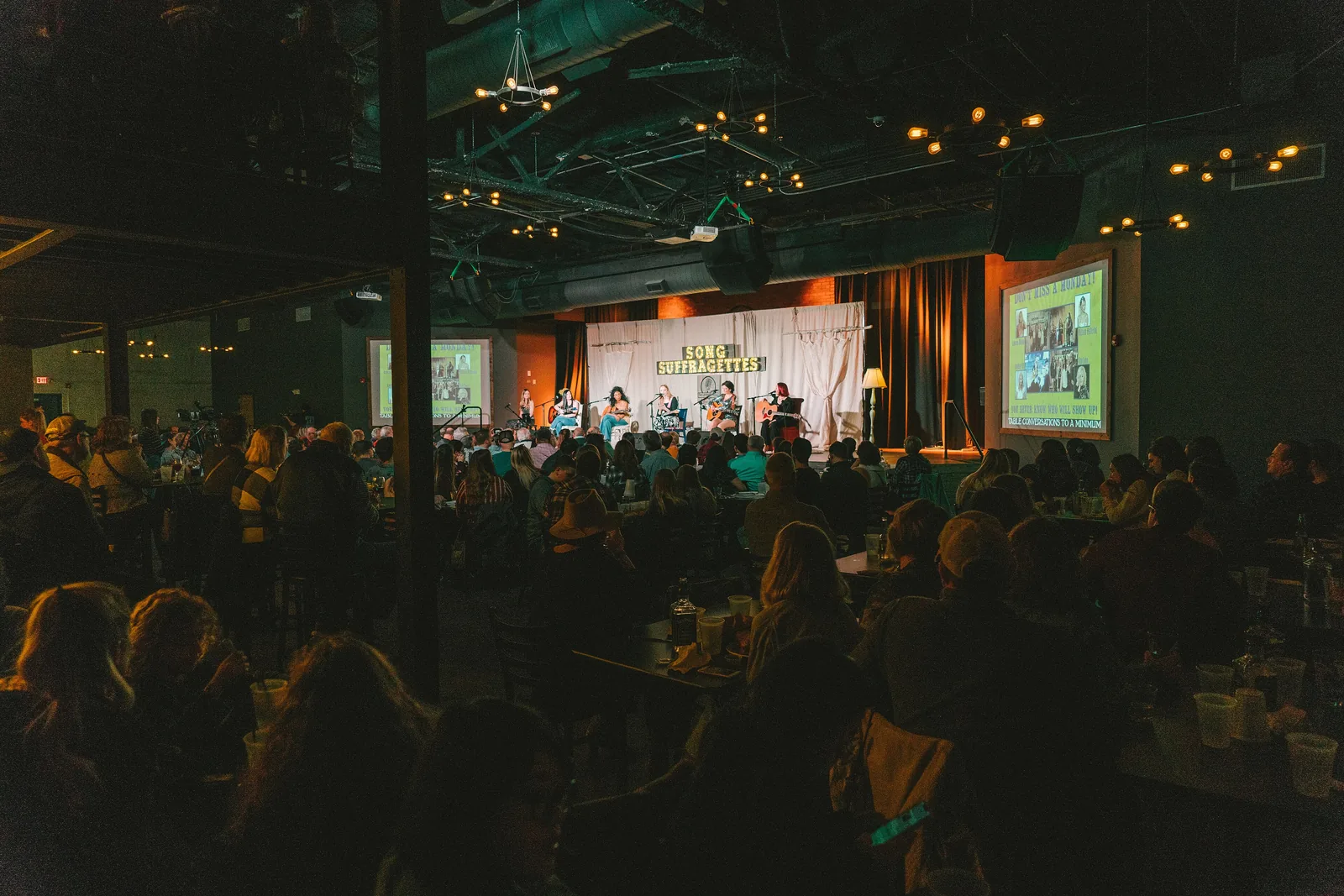 Songwriters perform on stage at a Song Suffragettes show.