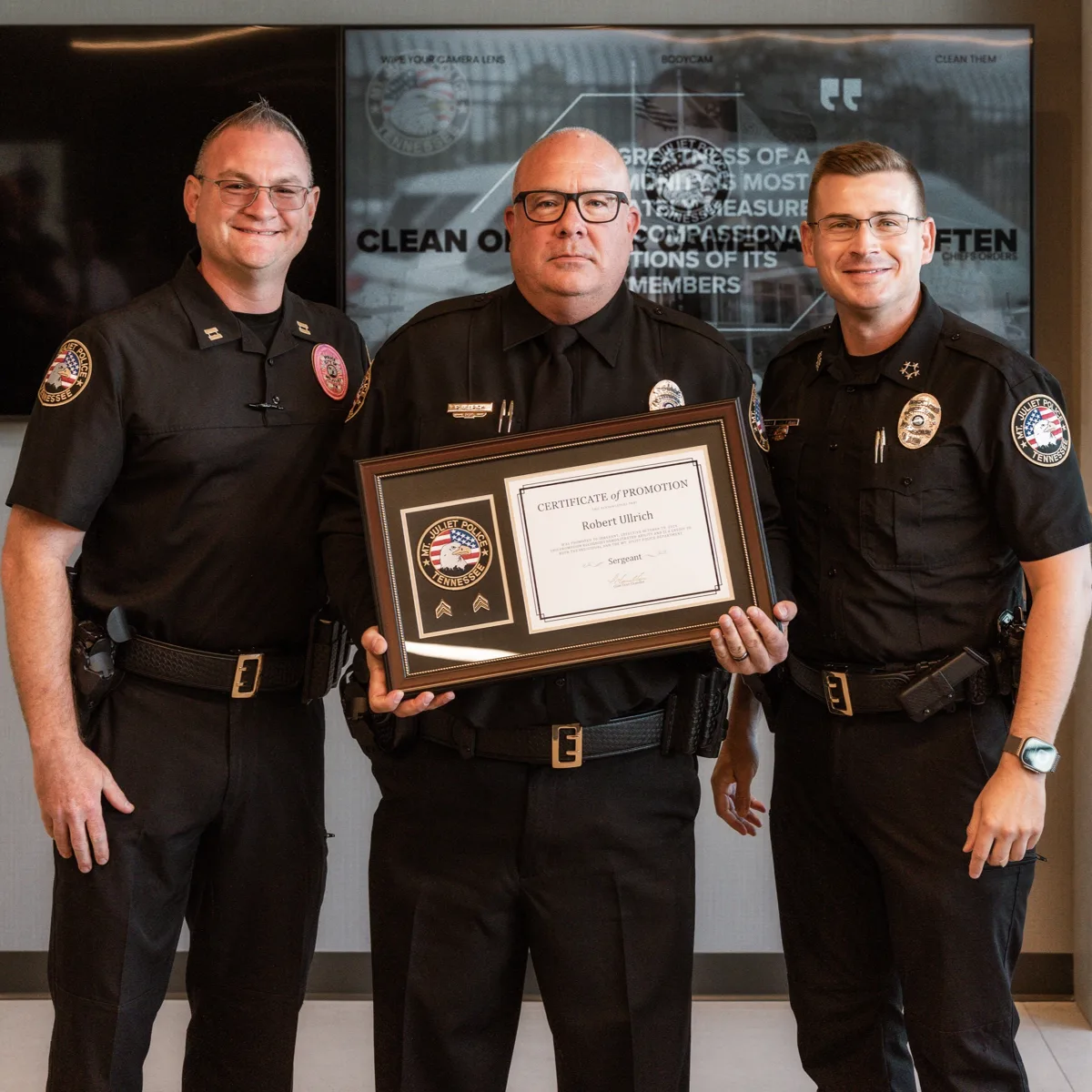Robert Ullrich holds his certificate of promotion to sergeant, standing between Capt. Jason Brockman and Chief Tyler Chandler.