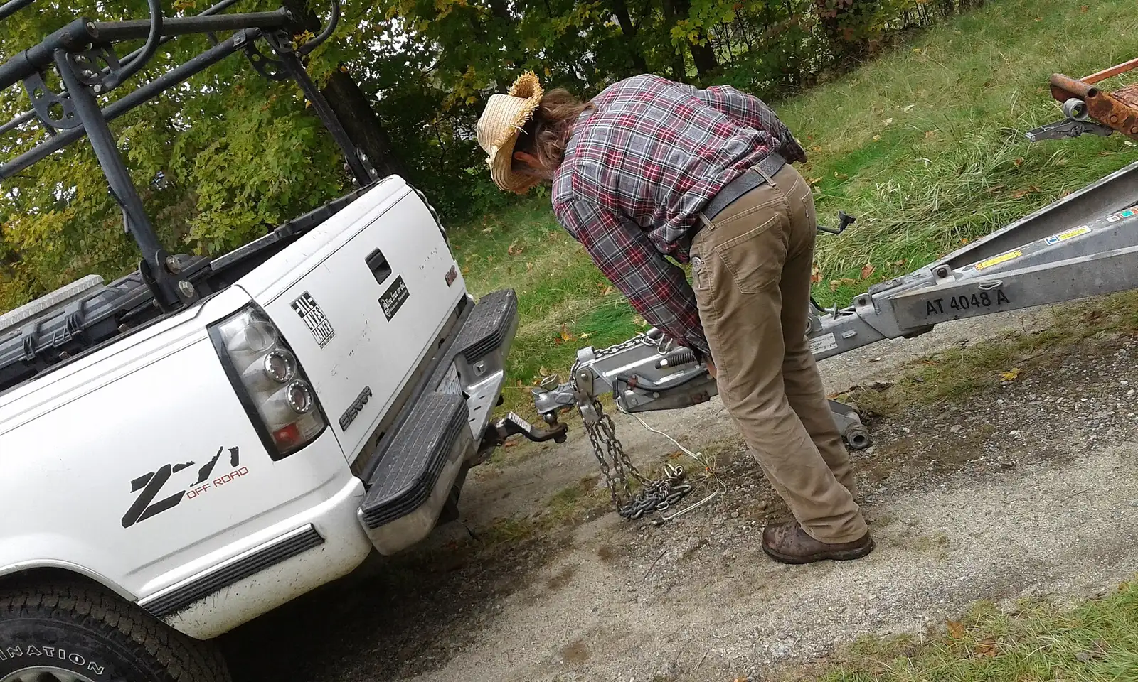 A family hitches a U-Haul trailer to a pickup truck in a residential driveway on moving day.