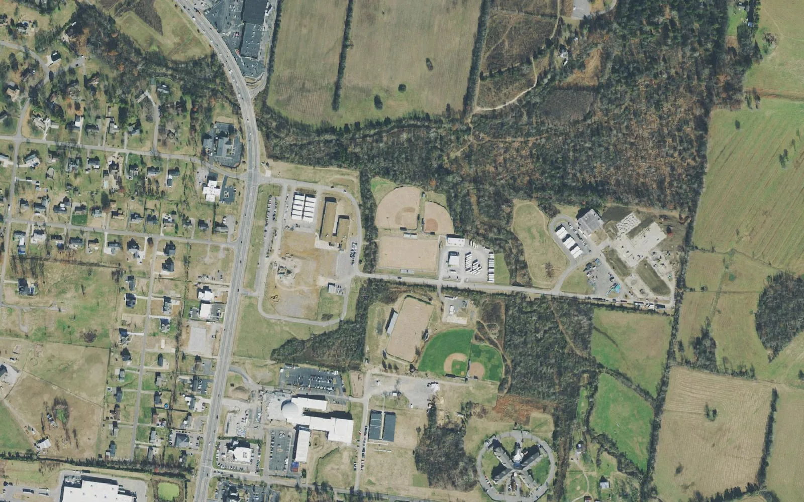 Aerial view of North Mt. Juliet Road between Interstate 40 and Division Street, with school buildings and ball fields east of the road and farmland beyond.