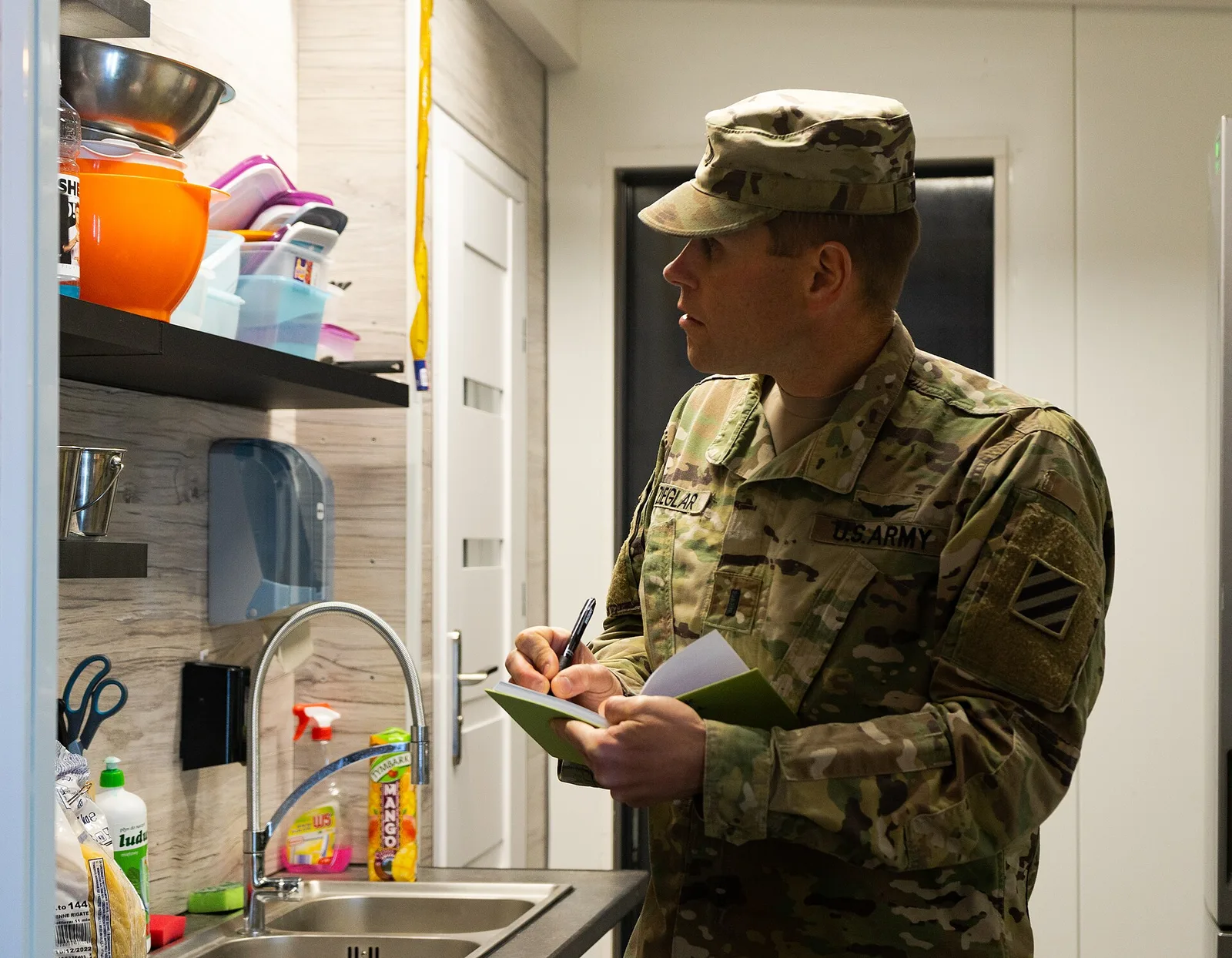 A preventive medicine officer checks food temperatures during a kitchen health inspection.