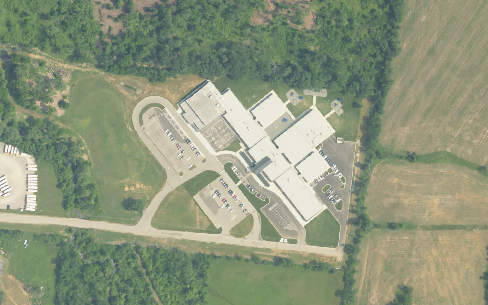 Stoner Creek Elementary School's building and car line loop off North Mt. Juliet Road, with woods and farm fields around the campus, seen from the air in 2023.