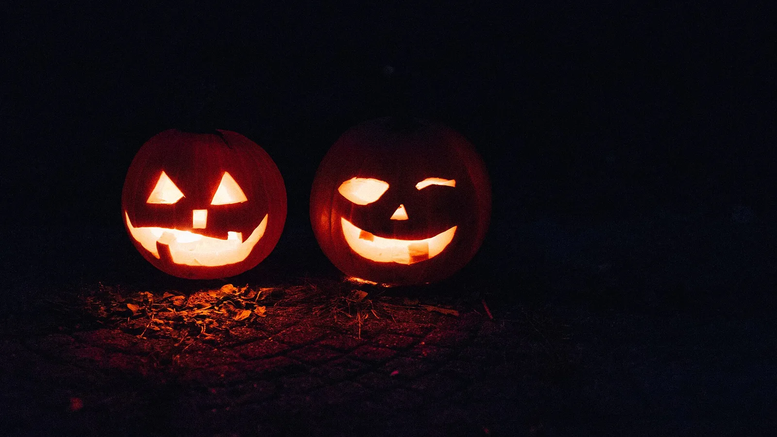 A carved jack-o'-lantern with a grinning face, the classic sign of a house giving out candy on Halloween.