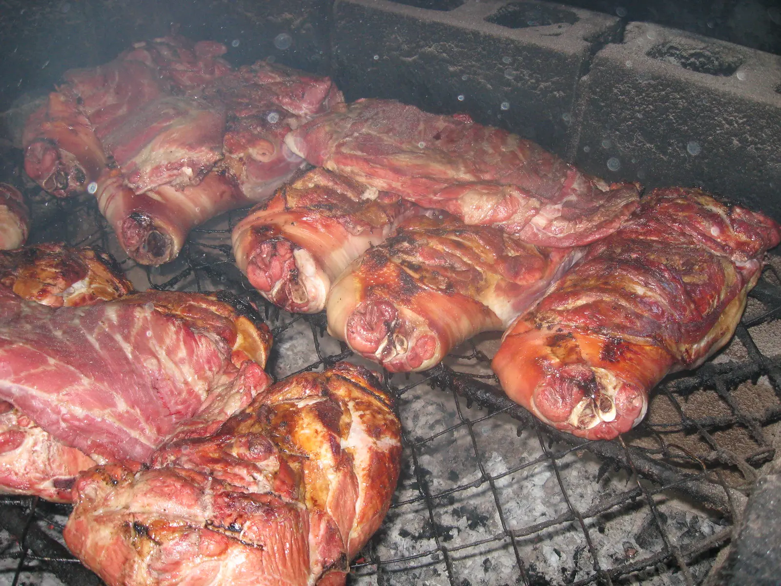 Pork shoulders and ribs cook over coals on the pit at Helen's barbecue.