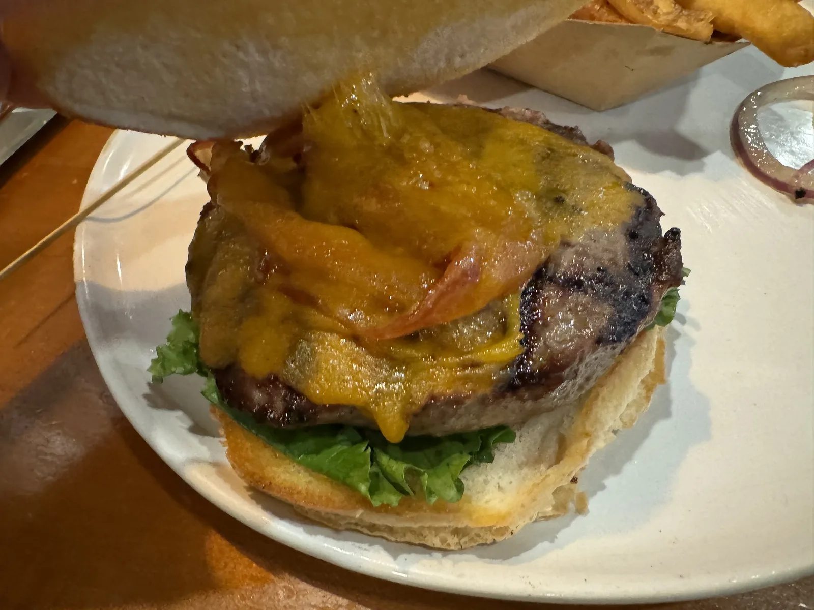 A bacon cheeseburger with lettuce on a toasted bun.